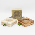Three natural stone soap dishes with a bar of soap on a white background
