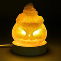 Decorative calcite lamp shaped like a pumpkin with a warm glow on a dark background